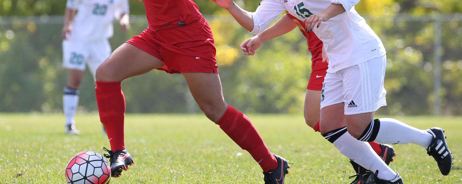 university of calgary dinos female soccer players kicking a soccer ball 