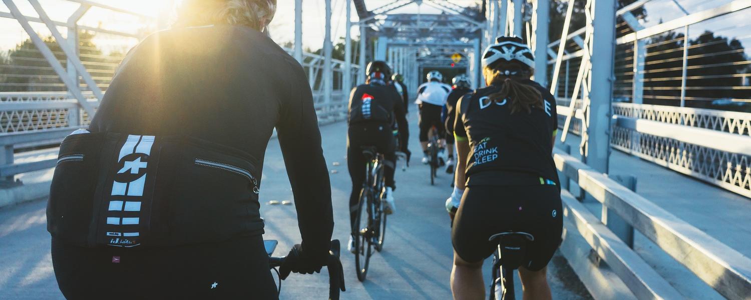 A team of cyclists biking across a pedestrian bridge