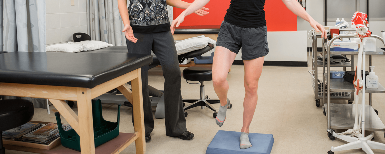 physiotherapist instructing a patient doing a single leg balance exercise